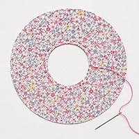 Fabric circle showing the basting stitch near the center hole.